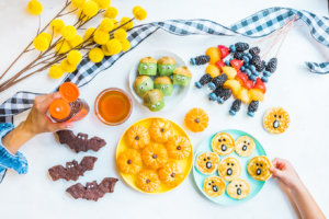 A creative arrangement of fruit and other treats with hands adding honey and decorations, evoking a festive atmosphere. A creative arrangement of fruit and other treats with hands adding honey and decorations, evoking a festive atmosphere.