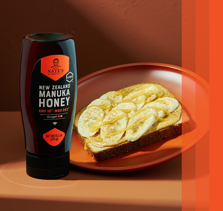 Nate's New Zealand Manuka Honey bottle beside a plate with honey-drizzled toast topped with banana slices.