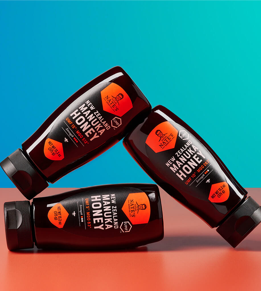 A bottle of New Zealand Manuka honey with a UMF 7+ rating, alongside cups of tea and lemon slices.