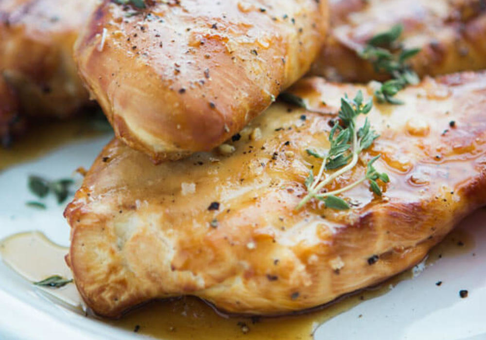 Grilled chicken breasts seasoned with herbs on a plate, showcasing a golden-brown sear and juicy appearance. Grilled chicken breasts seasoned with herbs on a plate, showcasing a golden-brown sear and juicy appearance.