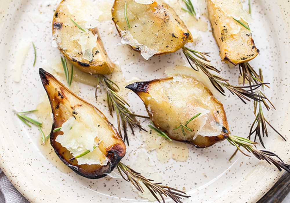 Roasted pears with cheese, rosemary and a drizzle of honey on a speckled plate. Roasted pears with cheese, rosemary and a drizzle of honey on a speckled plate.