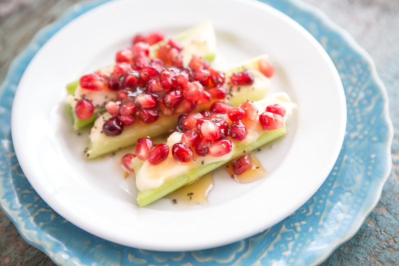 Cucumber slices topped with pomegranate seeds on a blue decorative plate.