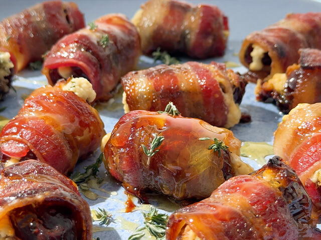 Array of dates stuffed with goat cheese and wrapped in bacon. Garnished with fresh thyme and honey.