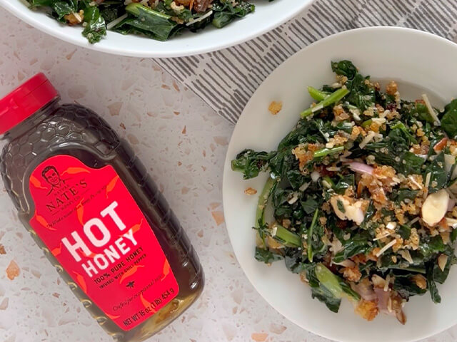 Bowl of kale and quinoa salad next to Nate's hot honey bottle.