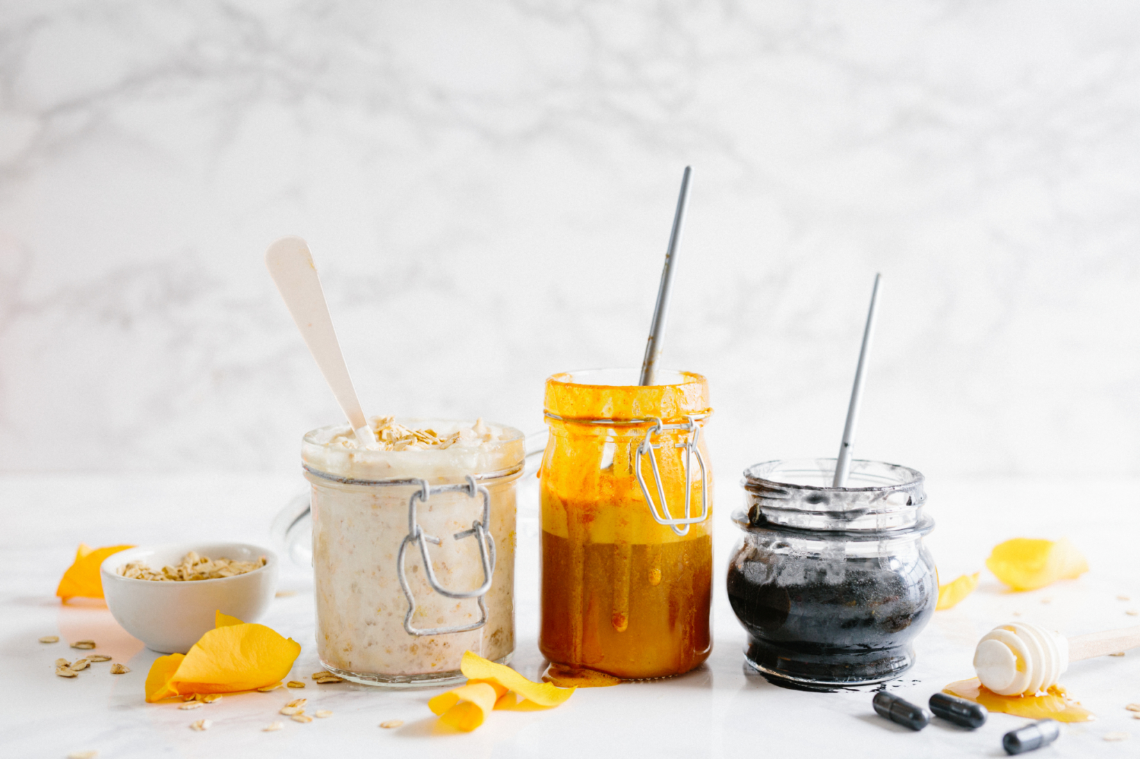 Jars of facial scrubs made with Nate's honey on a marble background.