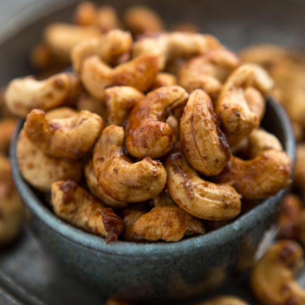 Honey spiced cashews in a rustic bowl on a dark table.
