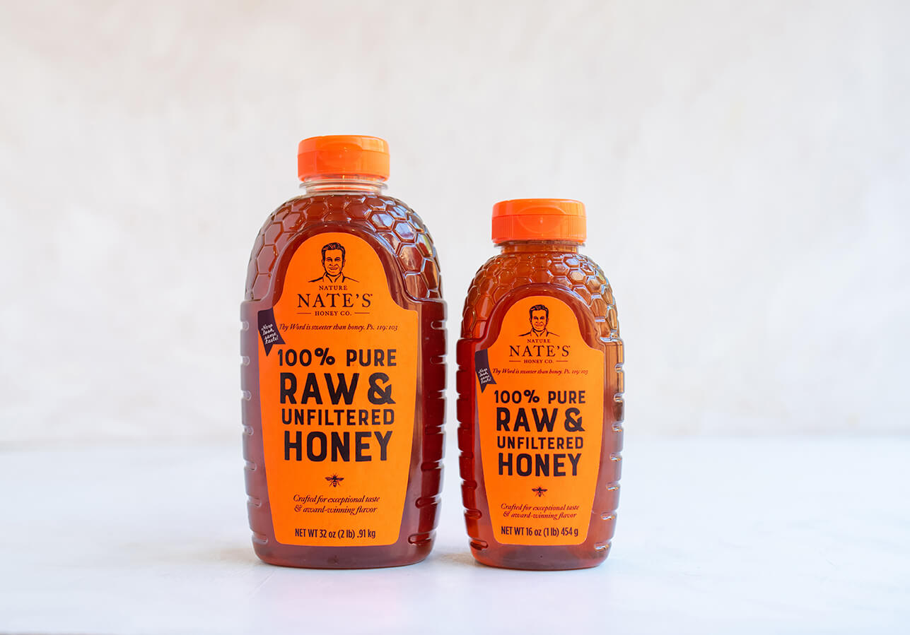 Two sizes of Nate's 100% pure raw & unfiltered honey bottles on a white surface.