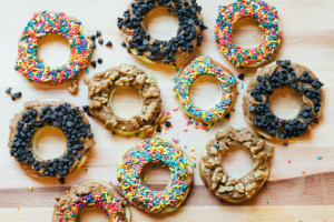 Apple rings topped with nut butter, chocolate chips, sprinkles and nuts on wood. Apple rings topped with nut butter, chocolate chips, sprinkles and nuts on wood.