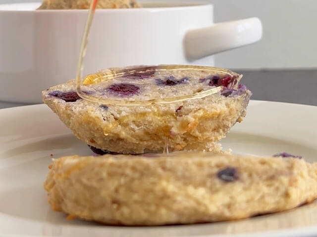 Blueberry banana English Muffin sliced in two with honey drizzle on top.