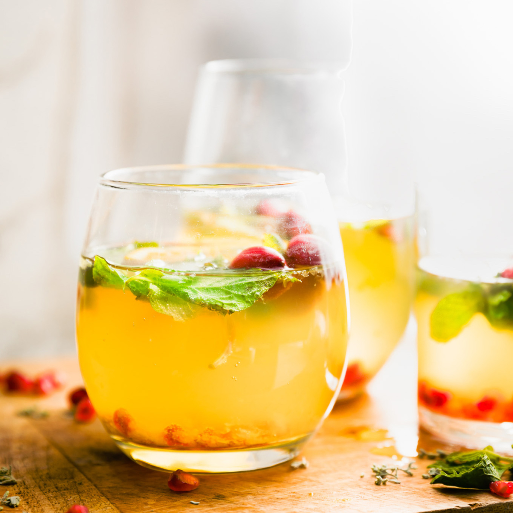 Golden-hued beverage with mint leaves and pomegranate seeds with an inviting ambience.