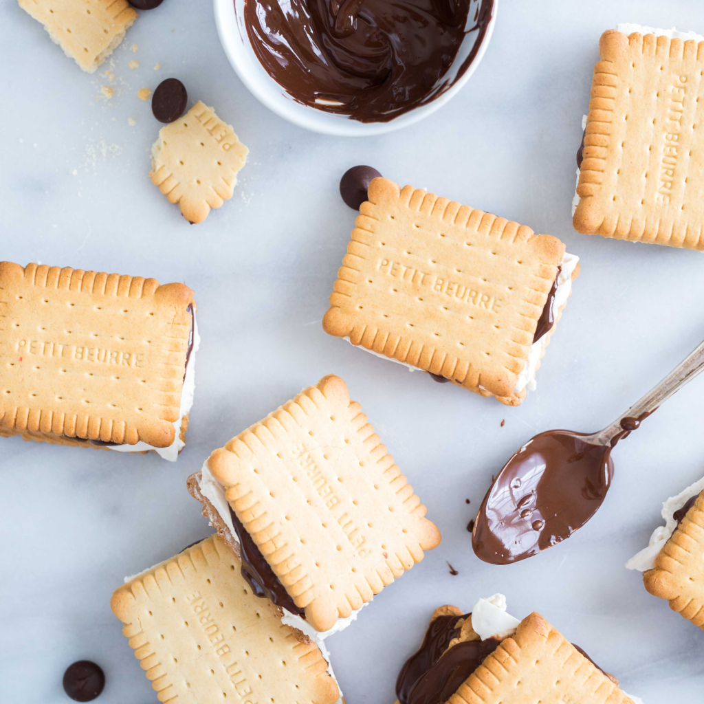 S'mores with chocolate and marshmallow filling, beside melted chocolate, on a marble surface. S'mores with chocolate and marshmallow filling, beside melted chocolate, on a marble surface.