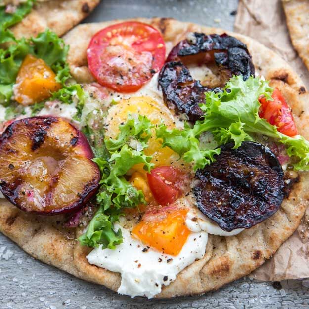 Flatbread pizza with grilled plums, tomatoes, goat cheese and fresh greens.
