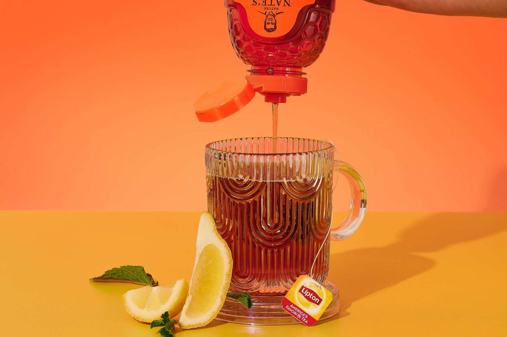 Nate's honey being drizzled into a mug of Lipton warm tea.