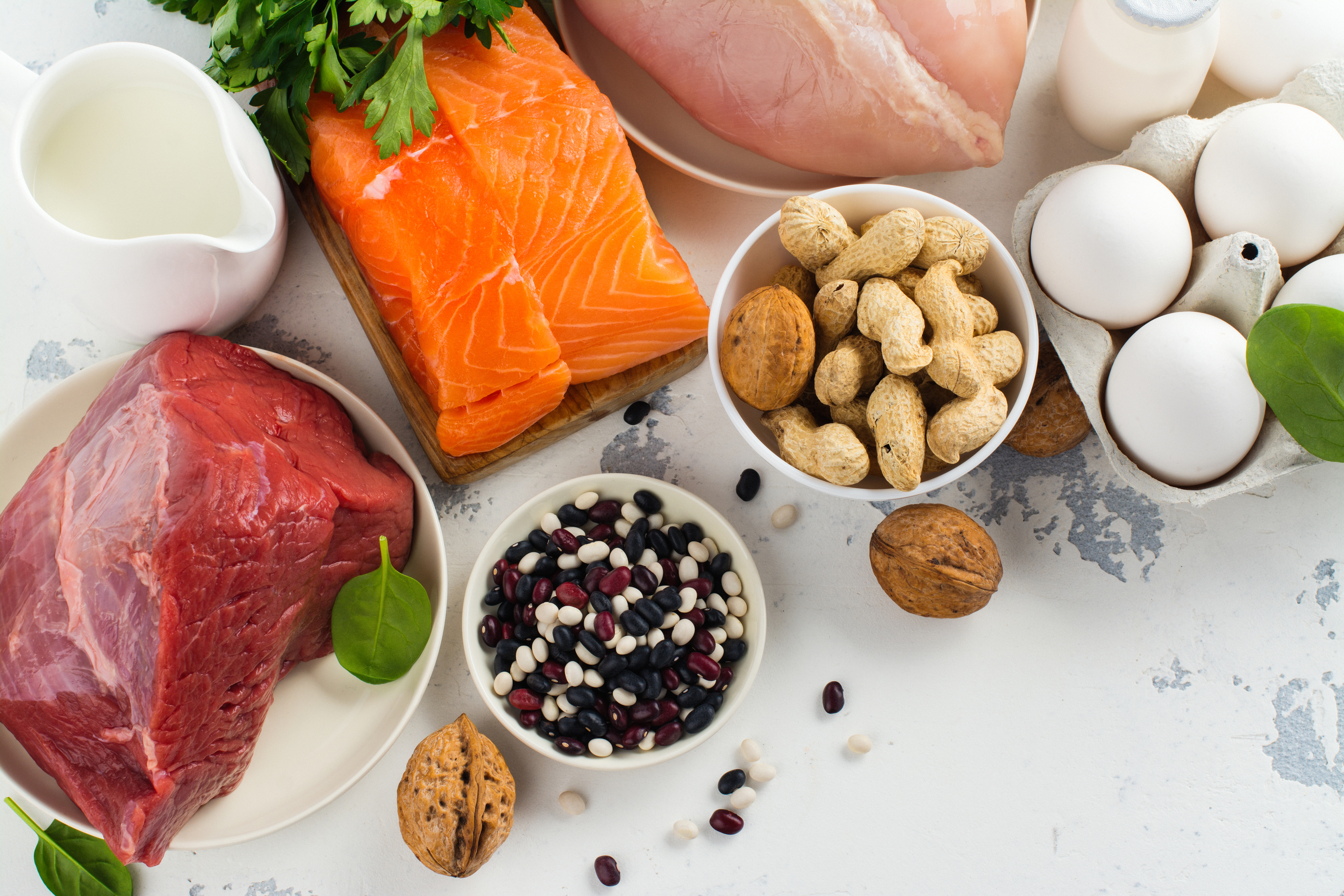 Assorted high-protein foods: meats, nuts, eggs, and milk on a light background. Assorted high-protein foods: meats, nuts, eggs, and milk on a light background.