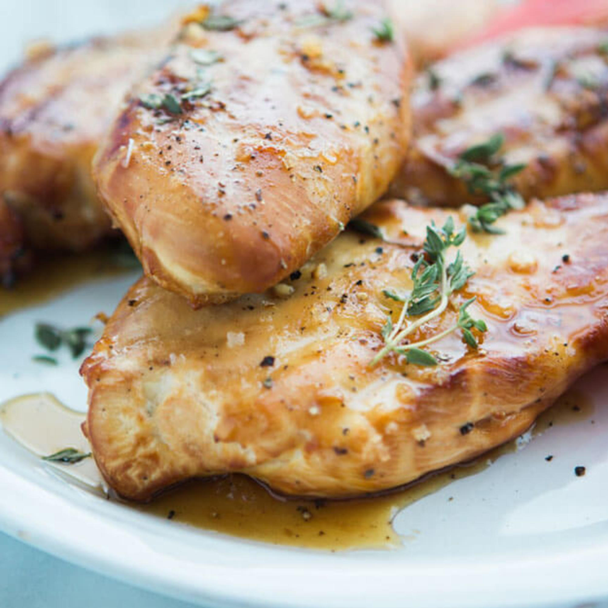 Grilled chicken breasts seasoned with herbs on a plate, showcasing a golden-brown sear and juicy appearance. Grilled chicken breasts seasoned with herbs on a plate, showcasing a golden-brown sear and juicy appearance.