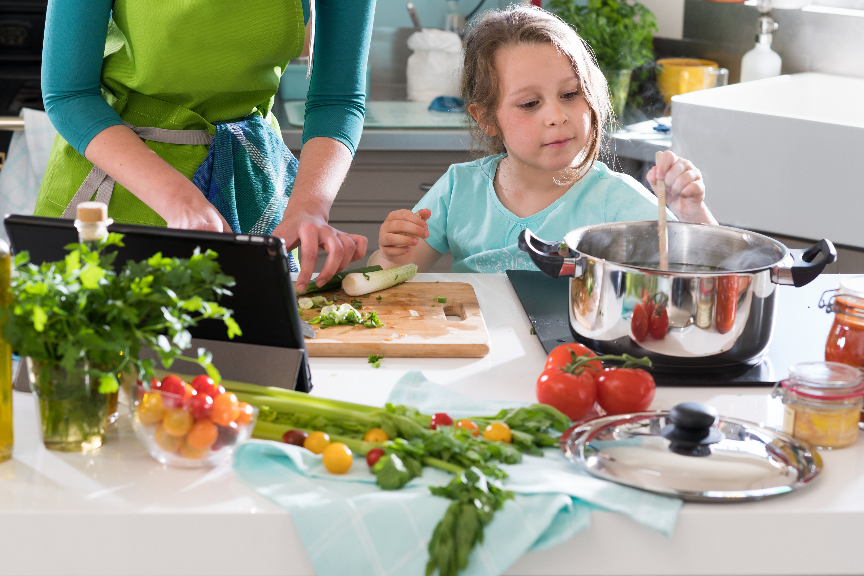 Adult and child cooking together with fresh ingredients in a bright kitchen. Adult and child cooking together with fresh ingredients in a bright kitchen.