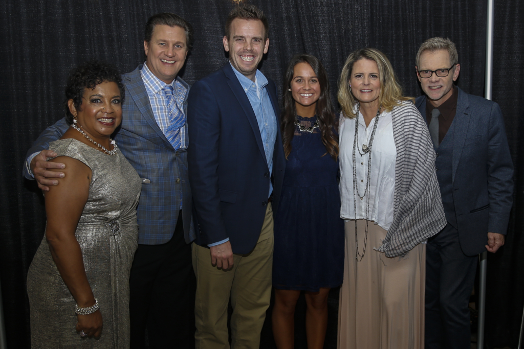The man Nature Nate with five adults, smiling at a formal indoor event.
