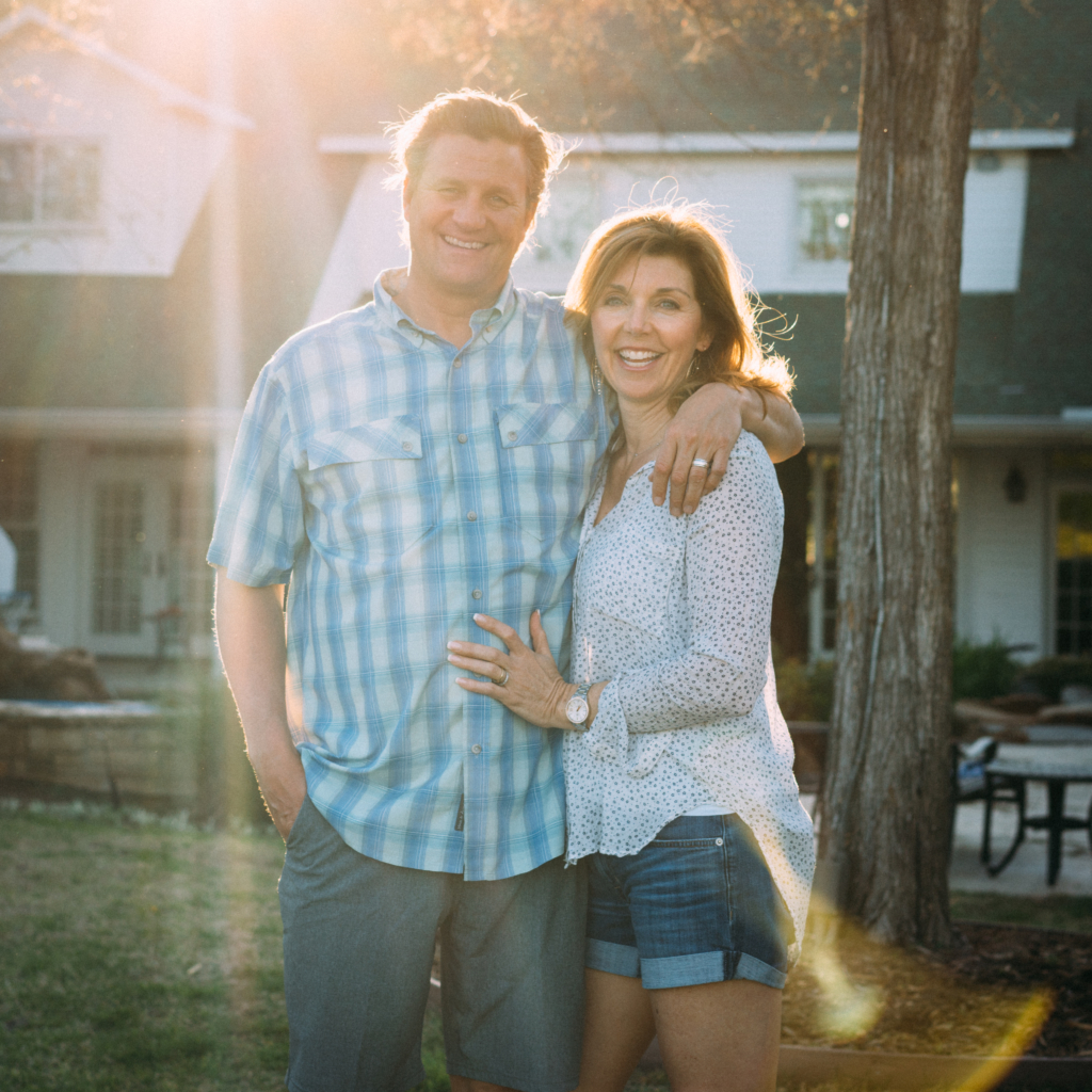 The man Nature Nate and his wife embracing outdoors with sun setting behind them, creating a warm glow. The man Nature Nate and his wife embracing outdoors with sun setting behind them, creating a warm glow.