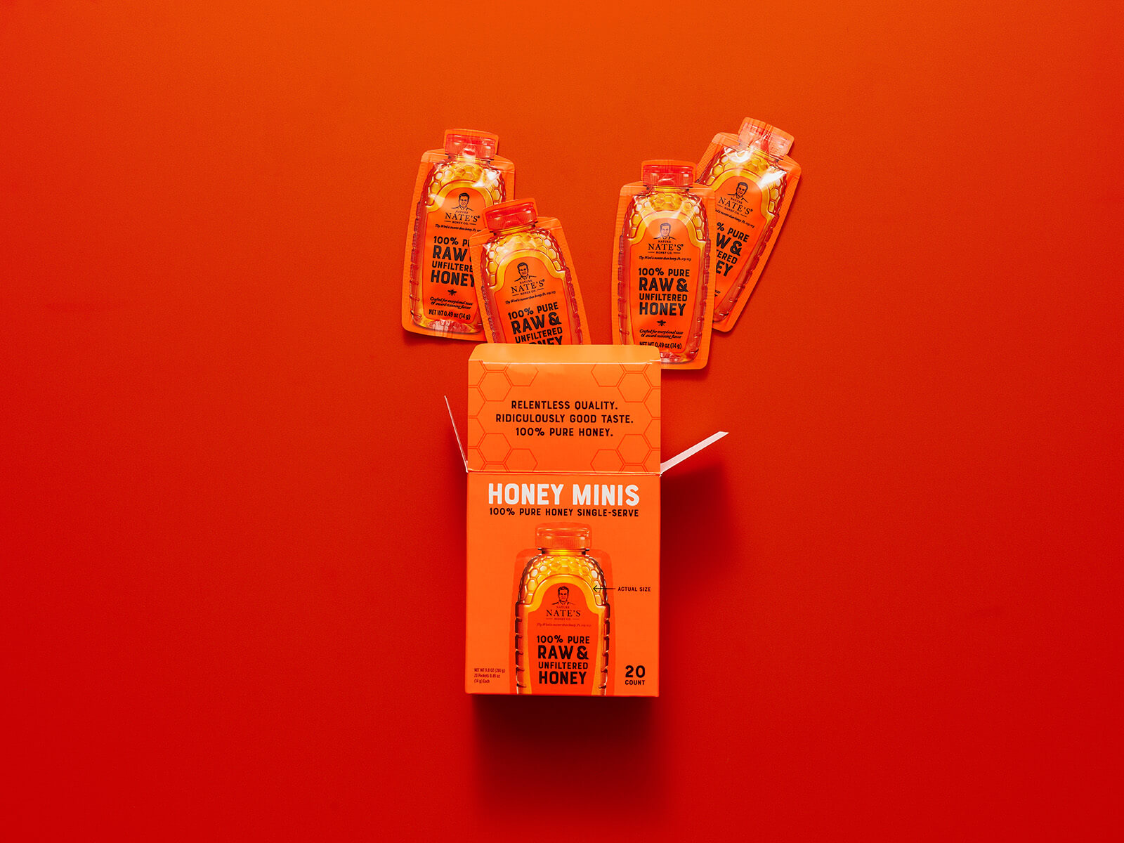 Orange honey minis box with top flap open and four honey mini packets popping out the box top.