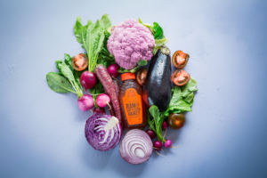 Assorted vegetables and Nate's honey bottle on a blue background.