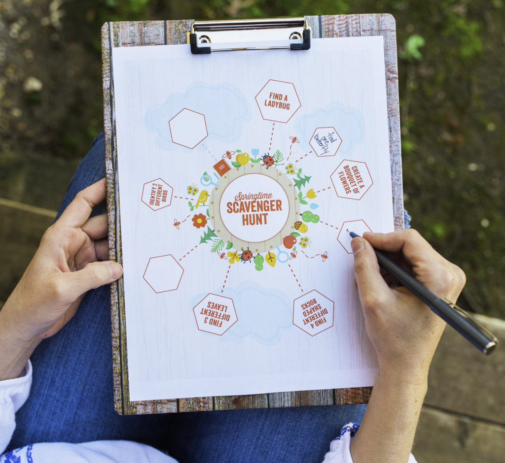 Hands holding clipboard with colorful scavenger hunt map, fun outdoor activity concept.