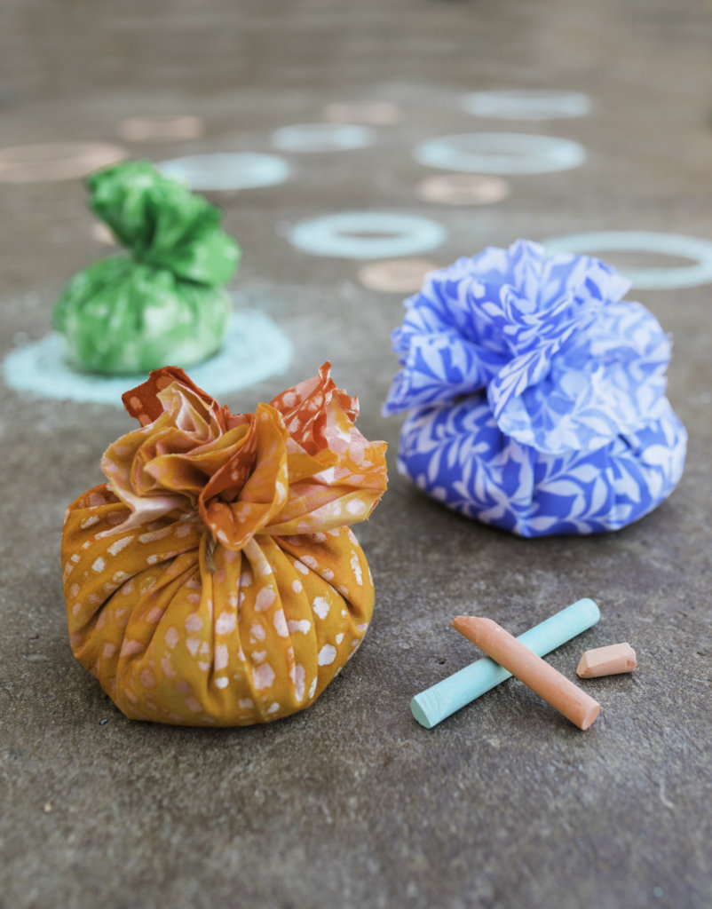 Colorful, round fabric bags filled with seeds with chalk and chalk-drawn circles on concrete. Colorful, round fabric bags filled with seeds with chalk and chalk-drawn circles on concrete.
