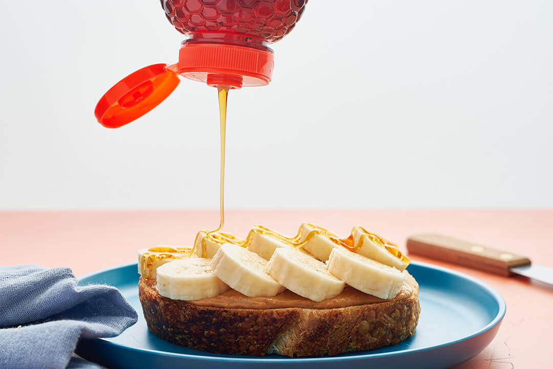 Nate’s honey being drizzled on peanut butter and banana toast.