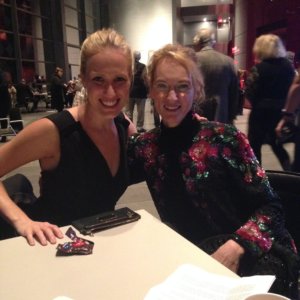 Two women posing for a photo together, one in a black top, the other in a floral top, both smiling.