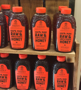 Shelf with bottles of Nature Nate's 100% Pure Raw & Unfiltered Honey.