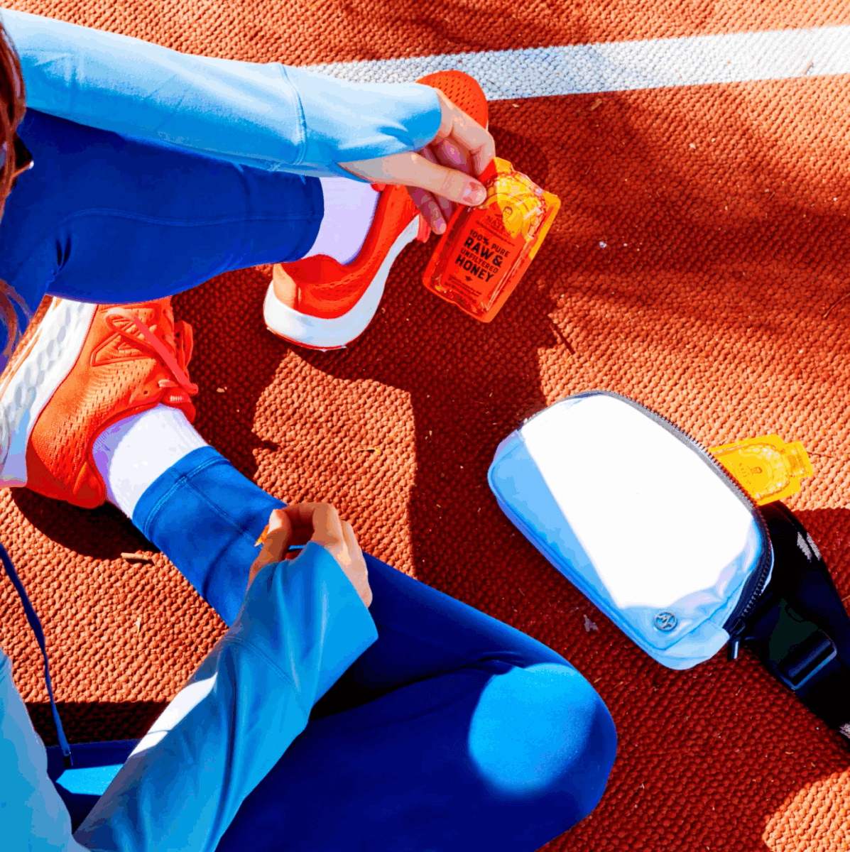 Athlete sitting on the ground holding a honey mini.